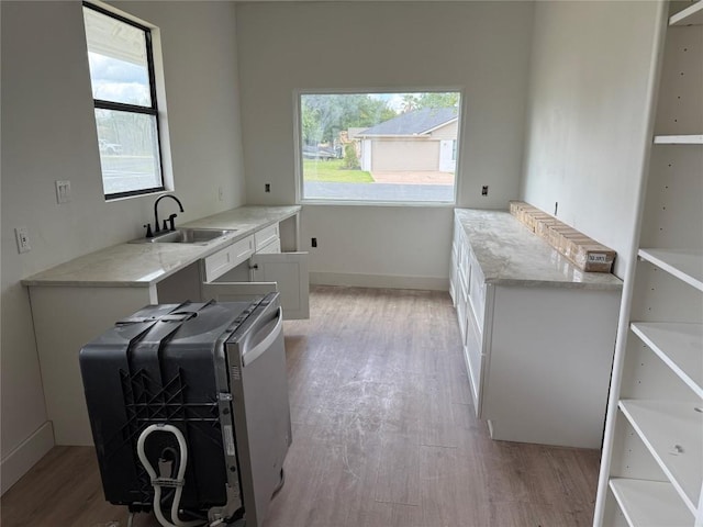 laundry room featuring light wood finished floors, a sink, and baseboards