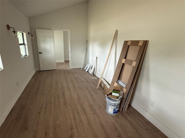 spare room featuring wood finished floors, vaulted ceiling, and baseboards