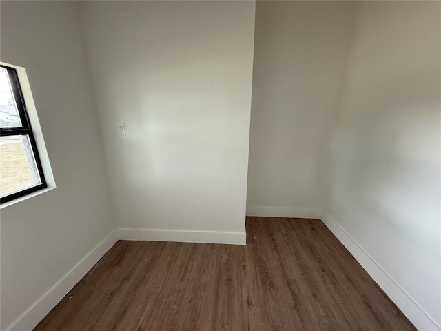 spare room featuring dark wood-style flooring and baseboards
