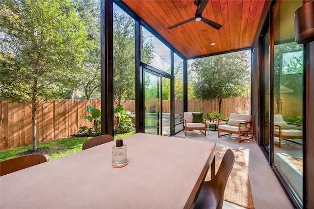sunroom with a wall of windows, healthy amount of natural light, a ceiling fan, and wooden ceiling