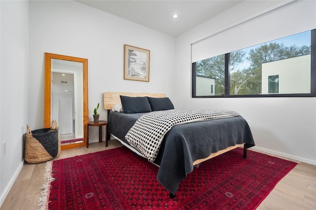 bedroom featuring wood finished floors, baseboards, and recessed lighting
