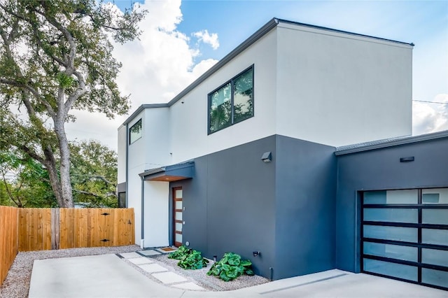 contemporary house featuring stucco siding, fence, a gate, and a garage
