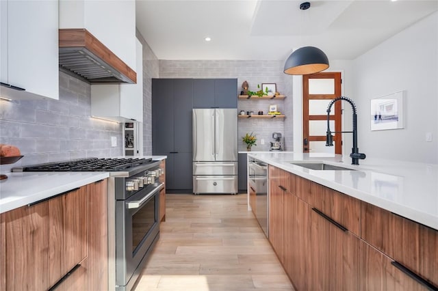 kitchen with appliances with stainless steel finishes, a sink, modern cabinets, light countertops, and recessed lighting