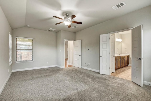 unfurnished bedroom with light carpet, lofted ceiling, ensuite bath, baseboards, and ceiling fan