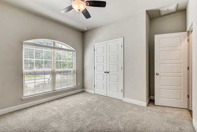 unfurnished bedroom with light carpet, baseboards, ceiling fan, and a closet