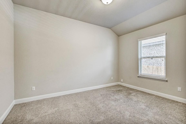 carpeted spare room with baseboards and lofted ceiling