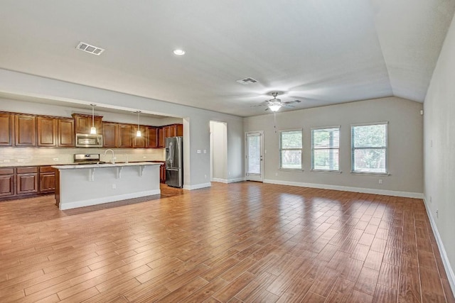 unfurnished living room featuring ceiling fan, baseboards, light wood-style floors, a sink, and recessed lighting