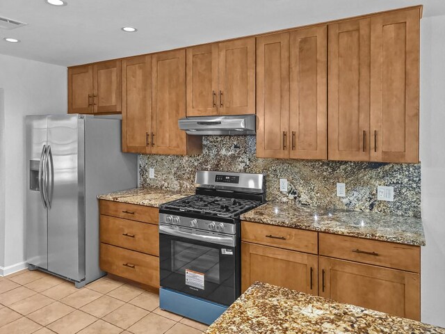 1801 Rock Creek Dr, Round Rock, TX 78681 - kitchen featuring appliances with stainless steel finishes, under cabinet range hood, brown cabinets, light tile patterned flooring, and light stone countertops
