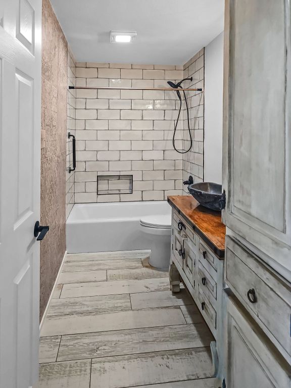 1801 Rock Creek Dr, Round Rock, TX 78681 - bathroom featuring wood finished floors, vanity, bathing tub / shower combination, and toilet