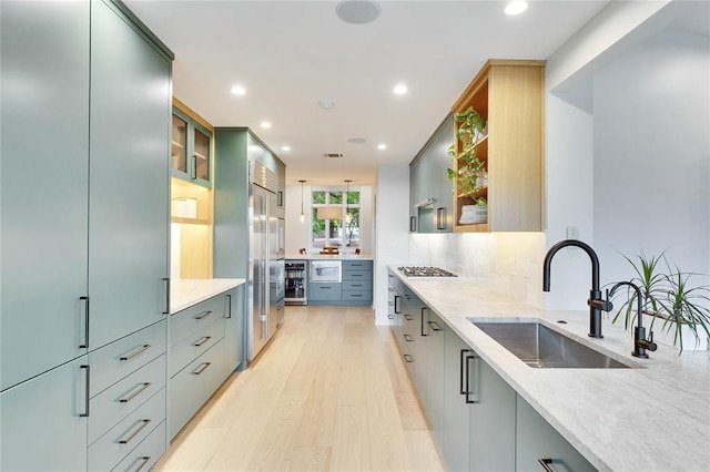 402 Buckeye Trl, West Lake Hills, TX 78746 - kitchen with a sink, recessed lighting, appliances with stainless steel finishes, light stone counters, and light wood-style flooring