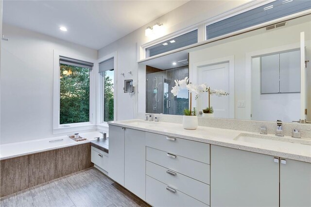 402 Buckeye Trl, West Lake Hills, TX 78746 - bathroom featuring a shower stall, double vanity, a bath, and wood finished floors