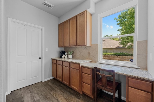 10216 Chaska Cv, Austin, TX 78739 - kitchen with brown cabinets, backsplash, light stone counters, and dark wood-style flooring