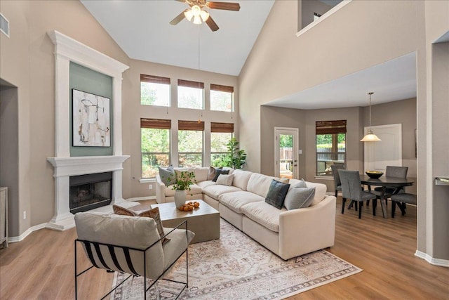 12920 Little Dipper Path, Austin, TX 78732 - living area featuring ceiling fan, light wood-style floors, high vaulted ceiling, a fireplace with raised hearth, and baseboards