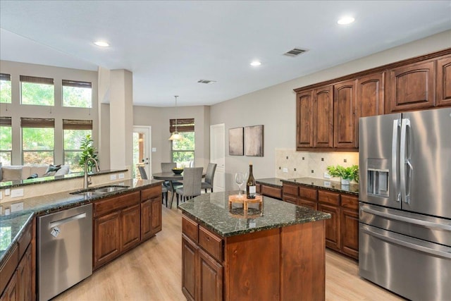 12920 Little Dipper Path, Austin, TX 78732 - kitchen with stainless steel appliances, a sink, light wood finished floors, tasteful backsplash, and dark stone counters