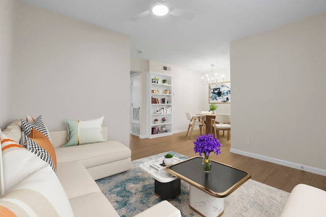 2401 Manor Rd Unit 235, Austin, TX 78722 - living room featuring a chandelier, wood finished floors, a ceiling fan, and baseboards