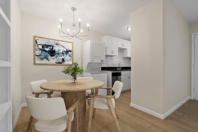 2401 Manor Rd Unit 235, Austin, TX 78722 - dining area with estacked washer and dryer, baseboards, a chandelier, and light wood-style flooring