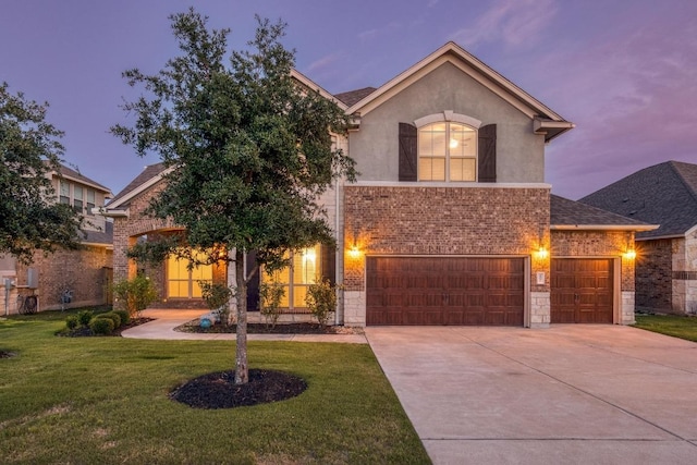 view of front facade featuring driveway, a front lawn, an attached garage, stucco siding, and brick siding