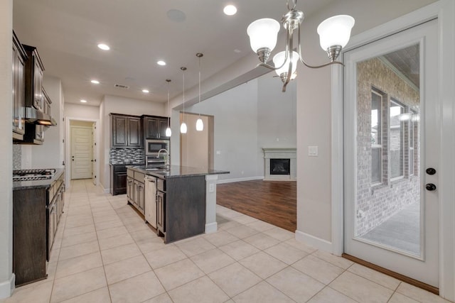 kitchen featuring dark brown cabinets, a chandelier, stainless steel appliances, open floor plan, and light tile patterned floors