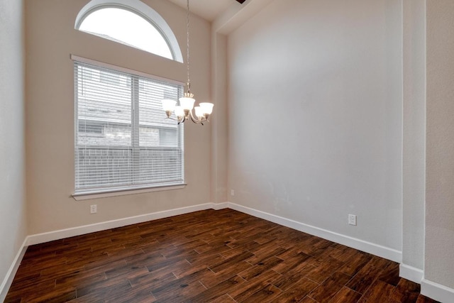 unfurnished room with dark wood-style flooring, a chandelier, and baseboards