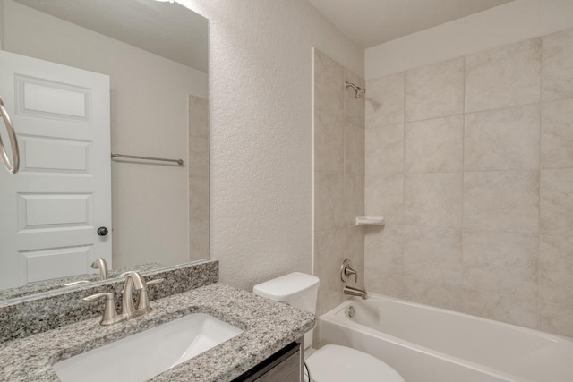 bathroom featuring toilet, a textured wall, tub / shower combination, and vanity