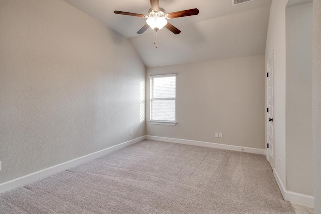 spare room featuring vaulted ceiling, a ceiling fan, baseboards, and light carpet