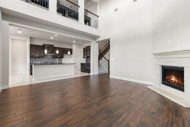3351 Vasquez Pl, Round Rock, TX 78665 - unfurnished living room featuring a warm lit fireplace, light wood-style flooring, a high ceiling, and stairs
