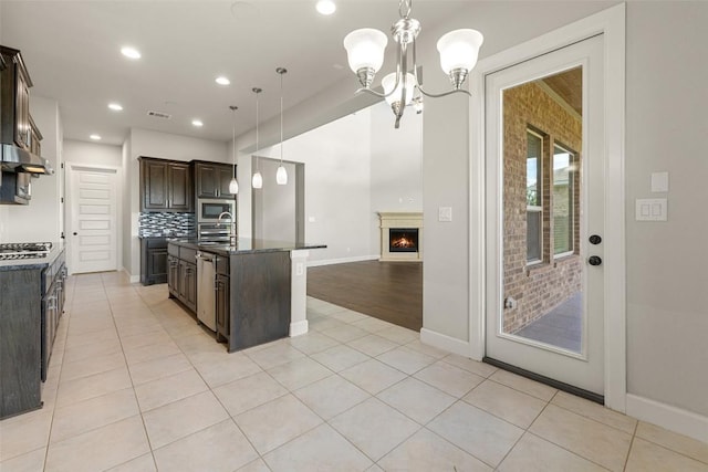 3351 Vasquez Pl, Round Rock, TX 78665 - kitchen featuring dark brown cabinets, stainless steel appliances, a chandelier, light tile patterned flooring, and decorative backsplash