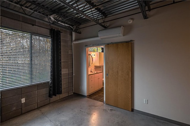 garage with a wall unit AC, a sink, and baseboards