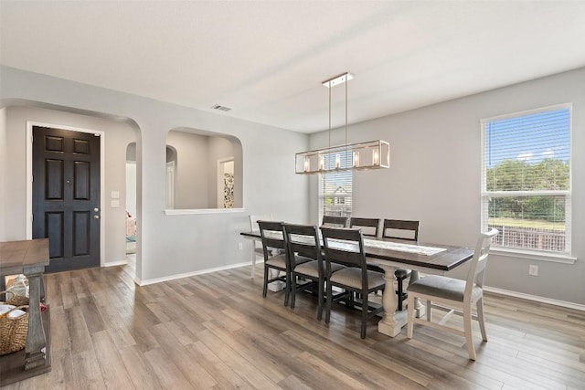 270 Johnny Cake Dr, Kyle, TX 78640 - dining area featuring baseboards, light wood finished floors, a chandelier, and arched walkways