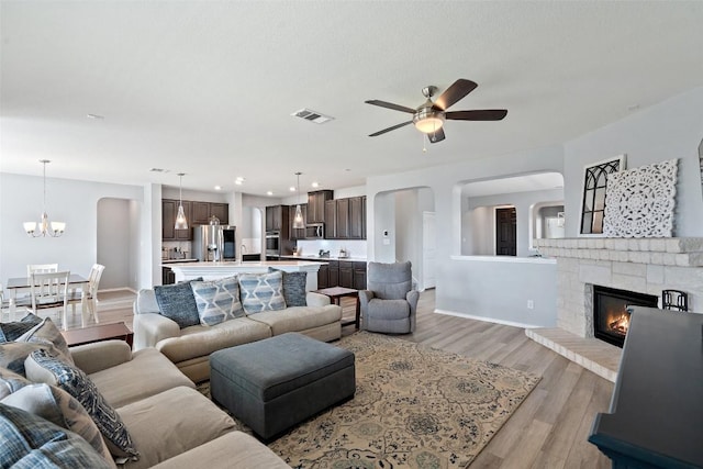 270 Johnny Cake Dr, Kyle, TX 78640 - living room with light wood-style floors, a ceiling fan, a chandelier, a fireplace, and baseboards