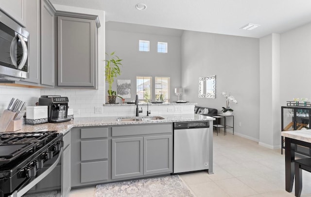 246 Salt Springs Rd, Kyle, TX 78640 - kitchen with gray cabinetry, appliances with stainless steel finishes, a sink, and light stone countertops