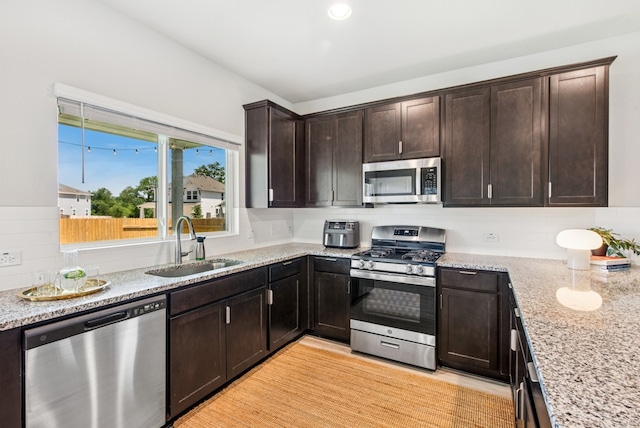 11 Bent Trail Ln, Georgetown, TX 78628 - kitchen with stainless steel appliances, a sink, light stone counters, tasteful backsplash, and dark brown cabinets