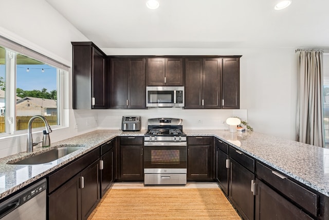 11 Bent Trail Ln, Georgetown, TX 78628 - kitchen with appliances with stainless steel finishes, a sink, light stone counters, recessed lighting, and dark brown cabinetry