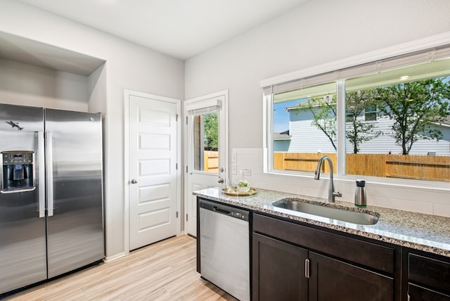 11 Bent Trail Ln, Georgetown, TX 78628 - kitchen featuring appliances with stainless steel finishes, a sink, light stone countertops, light wood finished floors, and dark brown cabinetry