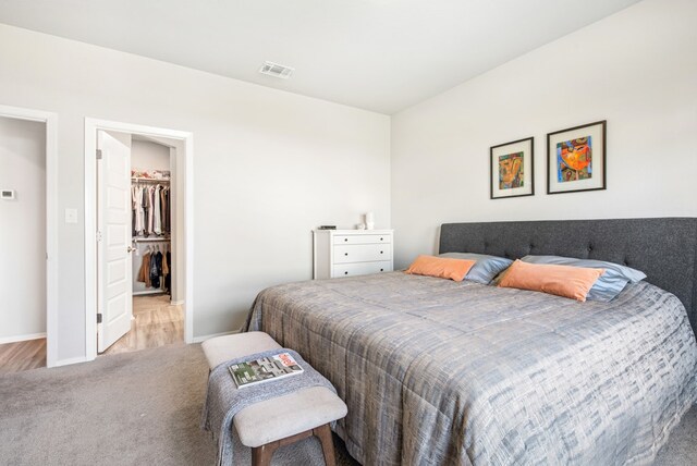 11 Bent Trail Ln, Georgetown, TX 78628 - bedroom with carpet flooring, a walk in closet, baseboards, a closet, and wood finished floors
