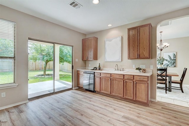 227 Woodlake Dr, Georgetown, TX 78633 - kitchen with stainless steel dishwasher, light wood-style flooring, light countertops, a chandelier, and brown cabinetry