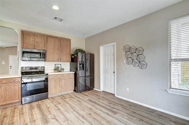 227 Woodlake Dr, Georgetown, TX 78633 - kitchen with appliances with stainless steel finishes, light wood-type flooring, light countertops, arched walkways, and recessed lighting
