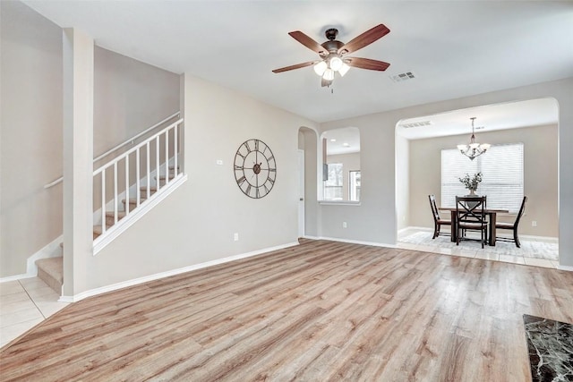 227 Woodlake Dr, Georgetown, TX 78633 - unfurnished living room featuring wood finished floors, stairs, ceiling fan, arched walkways, and a chandelier