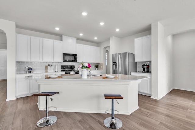 282 Crimson Ln, Kyle, TX 78640 - kitchen featuring black microwave, electric range oven, arched walkways, stainless steel refrigerator with ice dispenser, and a kitchen bar