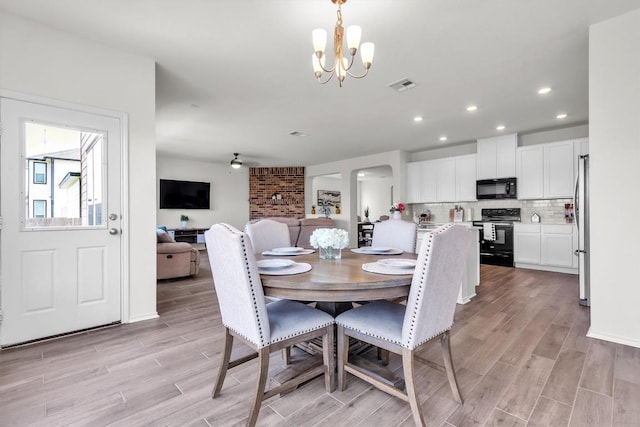 282 Crimson Ln, Kyle, TX 78640 - dining space featuring a chandelier, light wood-style floors, recessed lighting, and arched walkways