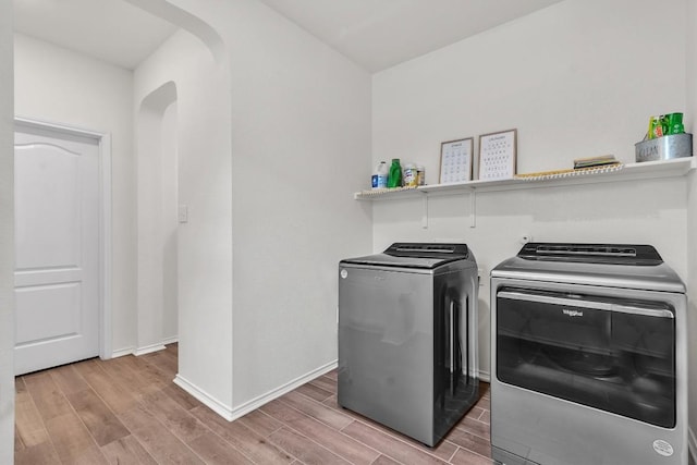 282 Crimson Ln, Kyle, TX 78640 - washroom with washer and clothes dryer, light wood-style flooring, arched walkways, and baseboards