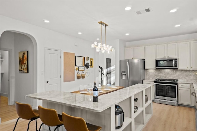286 Stone View Trl, Austin, TX 78737 - kitchen with stainless steel appliances, light wood-type flooring, a breakfast bar, tasteful backsplash, and light stone countertops