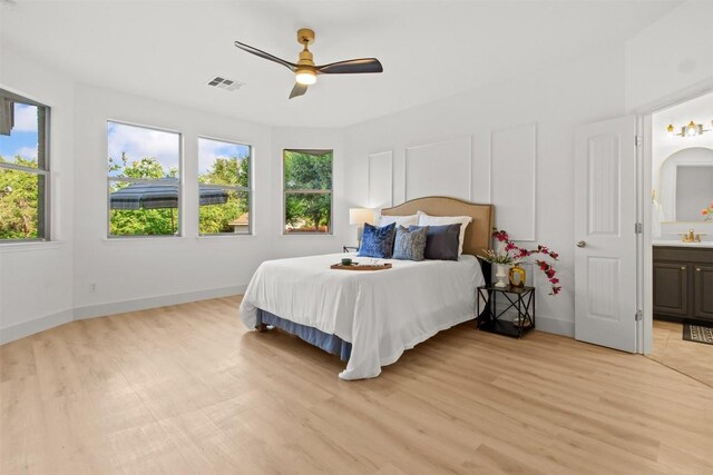 286 Stone View Trl, Austin, TX 78737 - bedroom featuring multiple windows, light wood-style floors, baseboards, and ensuite bath