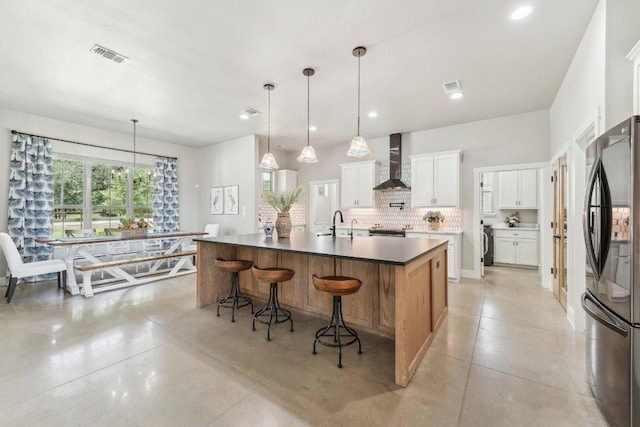 795 Van Bibber Rd, Salado, TX 76571 - kitchen featuring wall chimney exhaust hood, freestanding refrigerator, tasteful backsplash, recessed lighting, and a kitchen breakfast bar