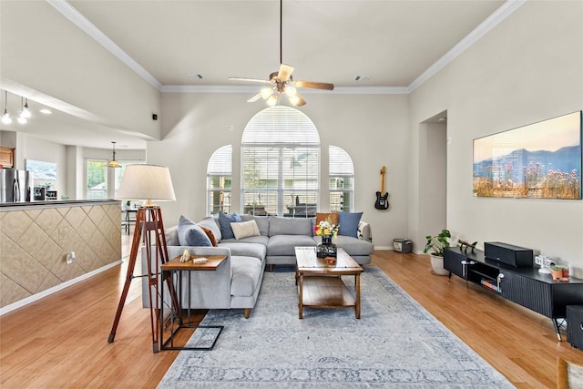 living room featuring light wood-type flooring, ceiling fan, ornamental molding, and baseboards