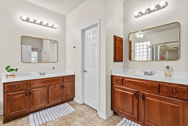 full bathroom featuring a stall shower, a ceiling fan, two vanities, tile patterned flooring, and baseboards