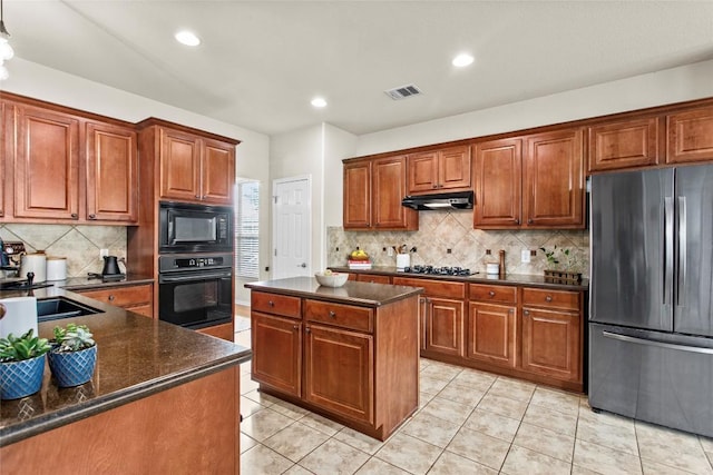 kitchen featuring black appliances, a sink, backsplash, brown cabinets, and under cabinet range hood