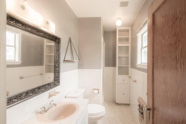 1408 W Clark St, Bartlett, TX 76511 - bathroom featuring tile walls, wainscoting, toilet, vanity, and plenty of natural light