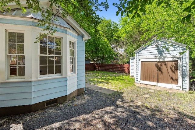 view of yard featuring fence, a detached garage, and an outbuilding