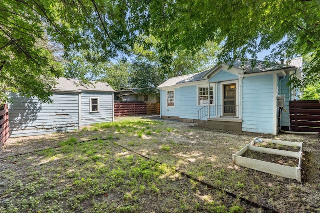 back of property featuring a fenced backyard and a vegetable garden